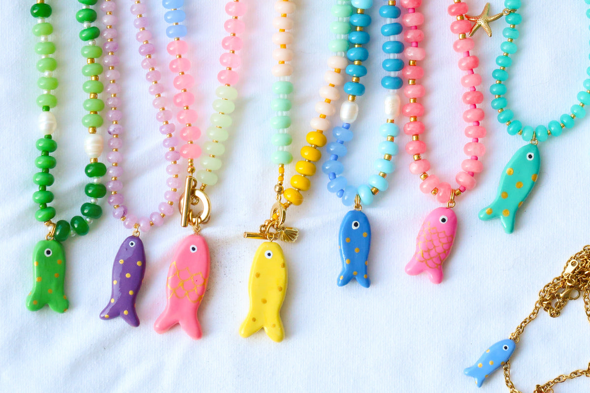 Colorful beaded necklaces with fish charms on a light blue background