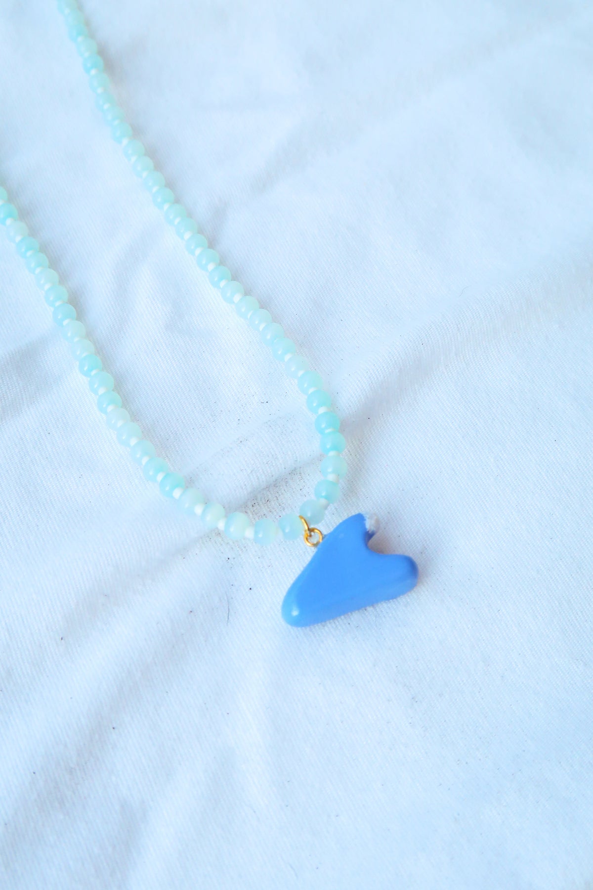 Necklace with a blue fish pendant on a light blue background