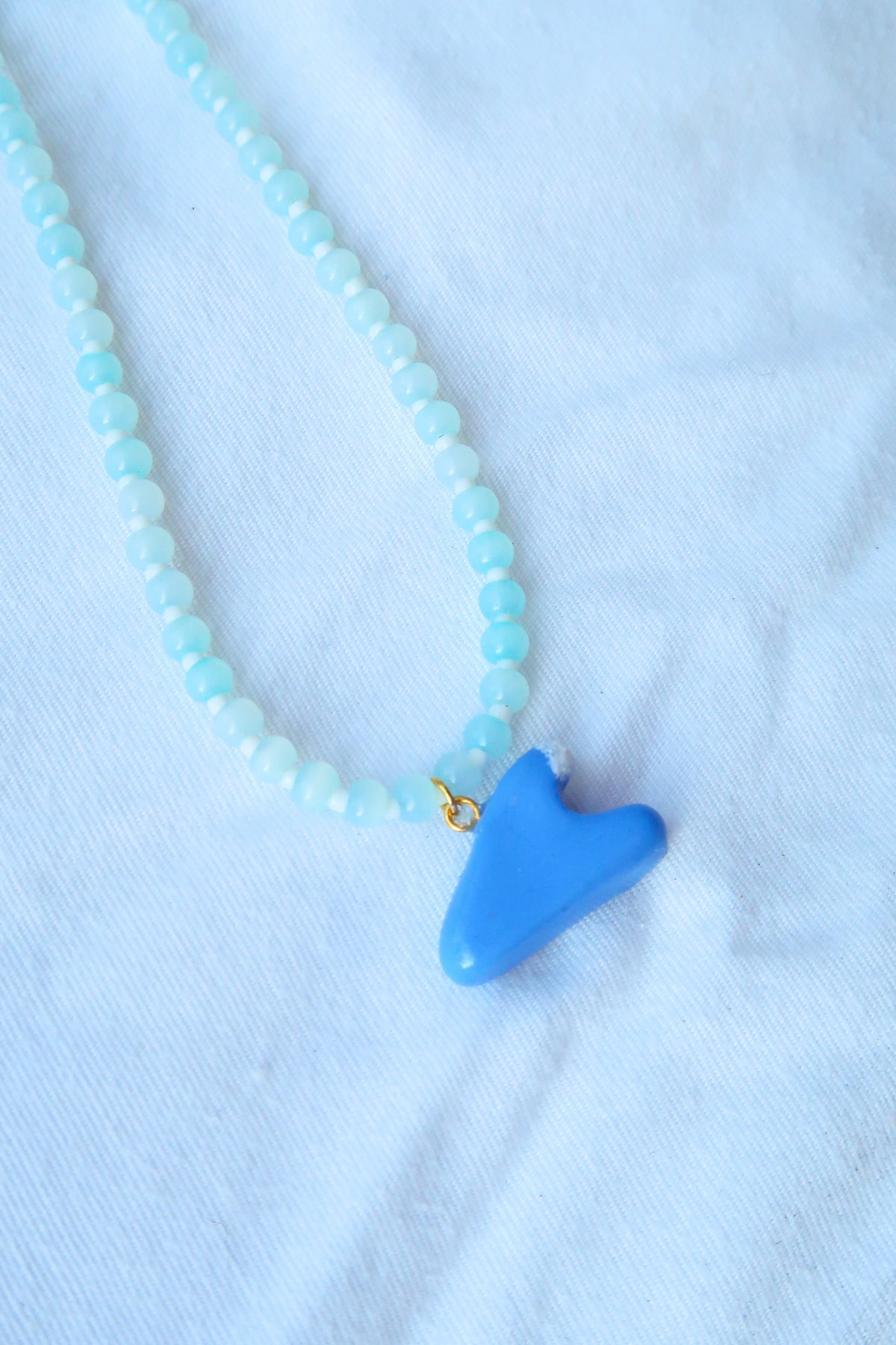 Necklace with blue fish-shaped pendant on a light blue background