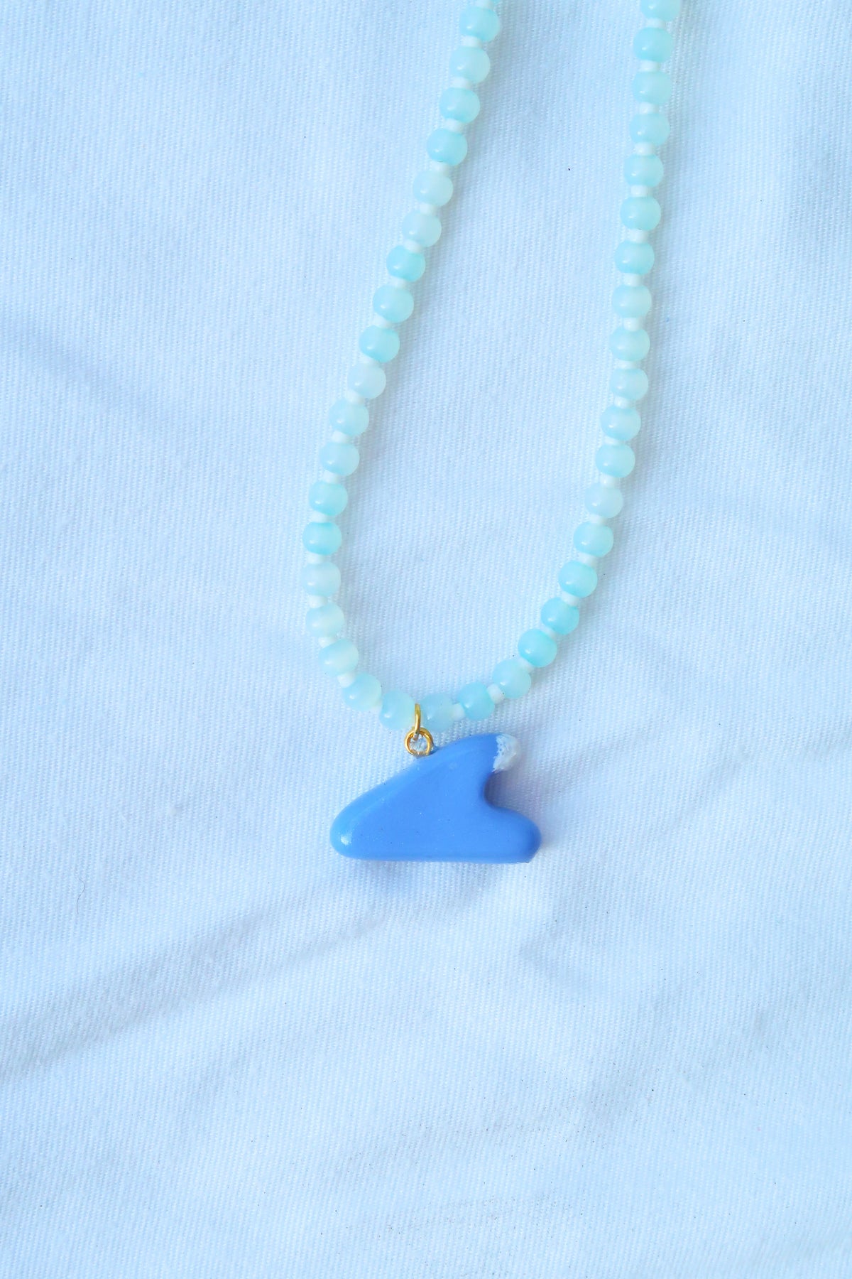 Necklace with a blue pendant on a light blue fabric background